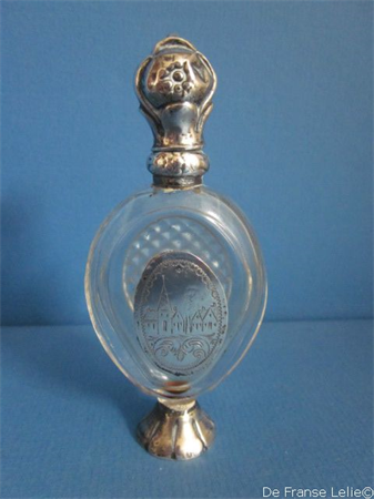 een antiek kristallen parfum flacon met zilveren dop