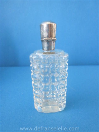 een antiek glazen parfumflacon met zilveren dop